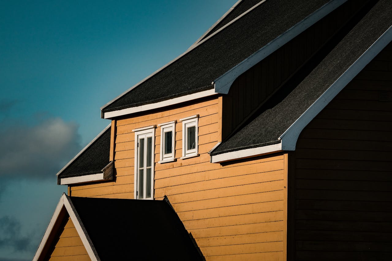 A bright yellow house facade with modern angular roof design under clear sky.
